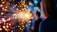 Young woman looking at magical glowing light burst with sparkling bokeh effect against dark background, creating dreamy atmospheric mood for fantasy concepts.