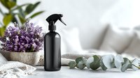 Black spray bottle with lavender bouquet and eucalyptus branch on soft textile, creating serene home decor atmosphere for natural cleaning products.