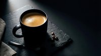 Black coffee cup with creamy espresso on dark slate surface with dramatic lighting and coffee beans for cafe menu design and beverage advertising.