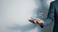 Businessman in dark suit holding digital network data visualization with glowing icons and connections, representing technology, cloud computing, and business intelligence solutions.