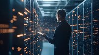 Young Asian male IT specialist examining digital data visualization in modern server room with glowing network connections and bokeh light effects.