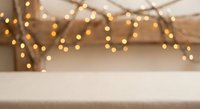 Warm bokeh lights create cozy atmosphere over empty wooden table surface for product display and holiday decorations in rustic interior setting.