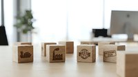 Wooden blocks with shipping and logistics icons arranged on office desk, representing global trade, delivery services, and supply chain management for business concepts.