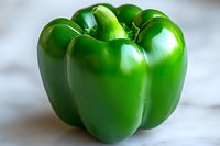 Fresh green bell pepper on white marble surface for healthy cooking and nutrition concepts.