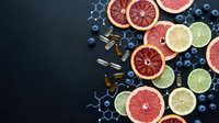 Fresh citrus fruits and blueberries with vitamin supplements on dark background. Healthy nutrition concept with natural antioxidants and wellness products.