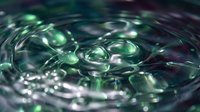 Water droplets creating ripples and bubbles in liquid surface with green reflections and dynamic motion patterns for nature and science concepts.