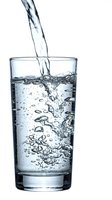 Fresh water pouring into clear glass with bubbles and splash on white background isolated for health and hydration concepts.
