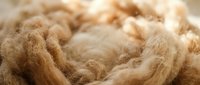 Natural brown wool fibers in soft coils ready for spinning into yarn, showcasing organic textile materials for crafting and handmade projects.