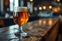 Glass of craft beer on rustic wooden bar counter with warm bokeh lights in background, amber liquid glowing in soft evening atmosphere.