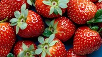 Fresh ripe strawberries with green leaves close up macro shot on dark background, natural organic berries pattern for healthy food design.