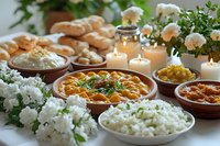 Indian curry dishes served with rice, naan bread and white flowers on decorated table with burning candles. Traditional authentic meal setting with aromatic spices.