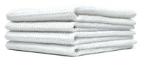 Stack of white waffle-textured cotton towels neatly folded on white background, isolated for home, spa, and bathroom decor projects.