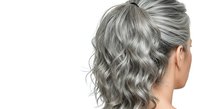 Mature woman with long wavy gray hair styled in a half-up bun, shown from behind against white background. Isolated stock photo suitable for hair care, aging gracefully, and salon design projects.