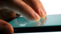 Close-up of male hand touching glowing turquoise touchscreen display with finger, technology interaction concept for apps and digital devices.