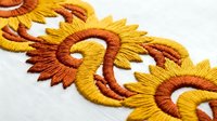 Golden yellow and orange embroidered floral pattern with decorative swirls on white fabric background for textile and craft design projects.