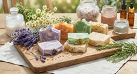 Natural handmade soap bars with lavender, herbs and essential oils on wooden board for organic skincare and aromatherapy wellness routine.