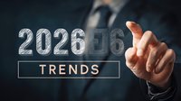 Businessman in dark suit pointing at glowing 2026 trends text on futuristic interface, representing business forecasting and strategic planning concept.