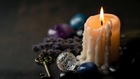 Burning candle with healing crystals, vintage key and coffee beans creating mystical spiritual atmosphere for meditation and wellness rituals.