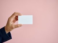 Hand holding blank white business card against pink background, suitable for branding, corporate identity, and marketing presentations.