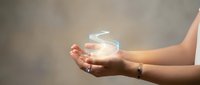 Female hands cupped together holding glowing holographic water drop symbol representing clean water conservation and environmental protection concept.