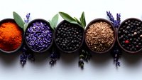 Aromatic spices and dried lavender flowers in black ceramic bowls arranged in row on white surface, decorative culinary composition with herbs and seasonings.