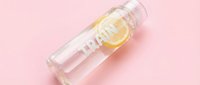 Clear water bottle with lemon slice inside on pink background, refreshing beverage mockup for product packaging and wellness branding.