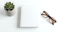 Minimalist workspace with blank notebook, succulent plant and eyeglasses on white background for creative projects and planning.