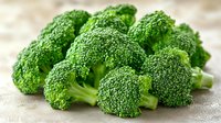 Fresh raw broccoli florets arranged on light gray background, macro shot showing detailed texture of green vegetable. Clean eating and healthy food concept.