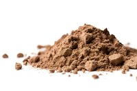 Heap of fine cocoa powder scattered on white surface, macro shot with selective focus and shallow depth of field showing natural texture and color.