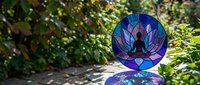 Stained glass meditation mandala with lotus flower design in vibrant blues and purples, perfect for spiritual and wellness projects in garden setting.