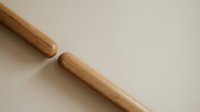 Wooden rolling pins on neutral beige background for baking and cooking preparation in modern kitchen setting.