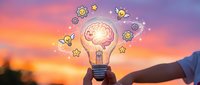 Hand holding illuminated lightbulb with brain and gear icons against sunset sky, representing innovation, creativity, and strategic thinking for business solutions.