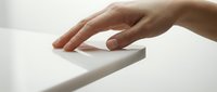 Close-up of hand touching white geometric surface, minimalist composition for design, architecture, technology, and product showcase concepts.