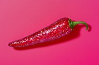 Red chili pepper covered in sparkly glitter on bright pink background, creative food art concept for spicy glamour and culinary decoration designs.