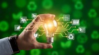 Hand holding glowing light bulb with digital circuit connections and eco-friendly icons on green background representing sustainable innovation.