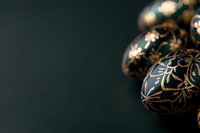 Elegant black and gold Christmas ornaments with intricate floral pattern on dark green background, creating luxurious holiday atmosphere. Selective focus adds depth.