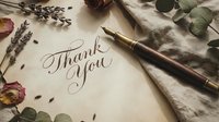 Elegant handwritten thank you note with calligraphy pen surrounded by dried flowers and eucalyptus leaves on vintage paper for gratitude expression.