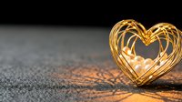 Golden heart-shaped light trails on asphalt surface creating romantic warm glow effect for Valentine's Day celebrations and love concepts.