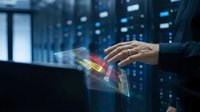 Businessman using digital tablet with holographic data visualization in modern server room for technology and business analytics applications.