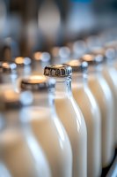 Fresh milk bottles with metal caps lined up in row, shallow depth of field creates soft bokeh effect, highlighting dairy freshness and purity.