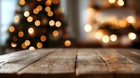 Rustic wooden table with blurred Christmas tree and warm bokeh lights in background creating festive holiday atmosphere for product display or design.