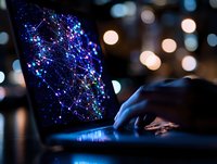 Glowing network visualization on laptop screen with blue and purple connections against dark background with bokeh lights, hands typing on keyboard.