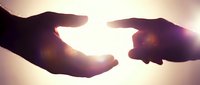 Two silhouetted hands gently cradling glowing light between them against a warm, blurred background, symbolizing care, protection, hope, and connection for wellness and support concepts.