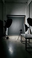 Professional photography studio setup with lighting equipment, backdrop and camera on tripod ready for commercial photo shoot in industrial loft space.