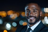 Confident African American businessman smiling at night with blurred city lights bokeh background creating professional urban atmosphere.