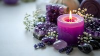 Purple candle burning surrounded by amethyst crystals, lavender flowers and healing stones for meditation, spa relaxation and spiritual wellness rituals.