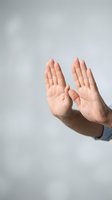 Two open hands raised upward in protective or receiving gesture against neutral gray background for wellness and spiritual concepts.