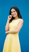 Young confident woman in yellow dress posing thoughtfully against bright blue background for business and lifestyle concepts.