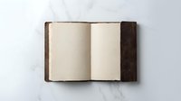 Open vintage leather-bound book with blank cream pages on white marble surface. Classic hardcover journal ready for writing, notes, or creative projects.
