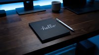 Dark notebook with hello inscription and pen on wooden desk in moody blue light, workspace concept for business and creativity.
